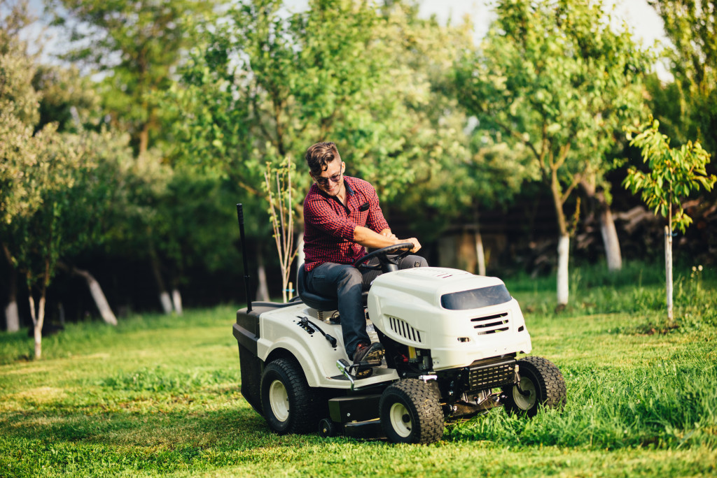 a man mowing a garden with vehicle